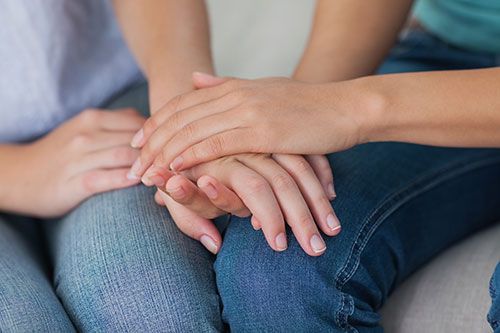 One person holding another person's hand in support and encouragement. Symbolic of betrayal trauma coaching.