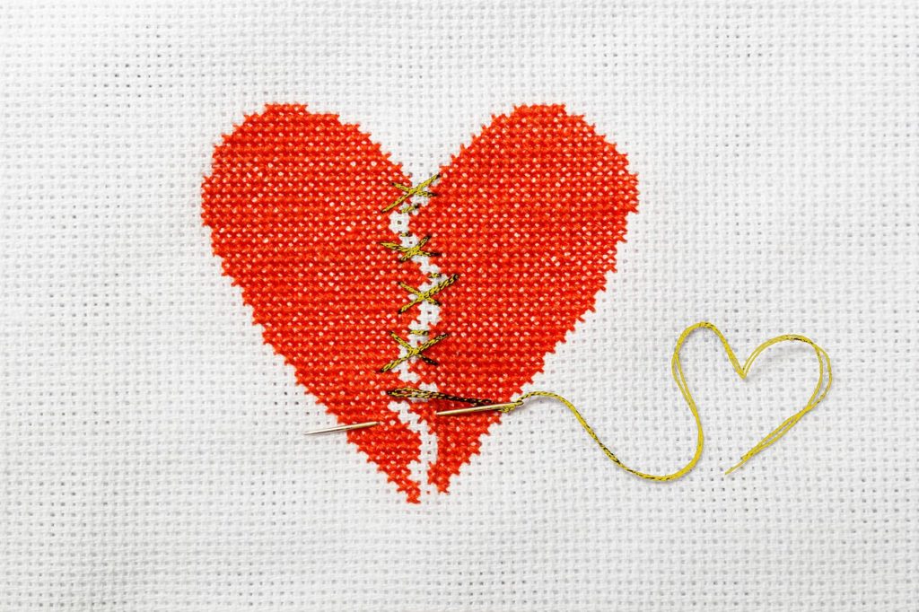 cross stitched heart torn in two stiched together with golden thread for betrayal trauma from sex addiction